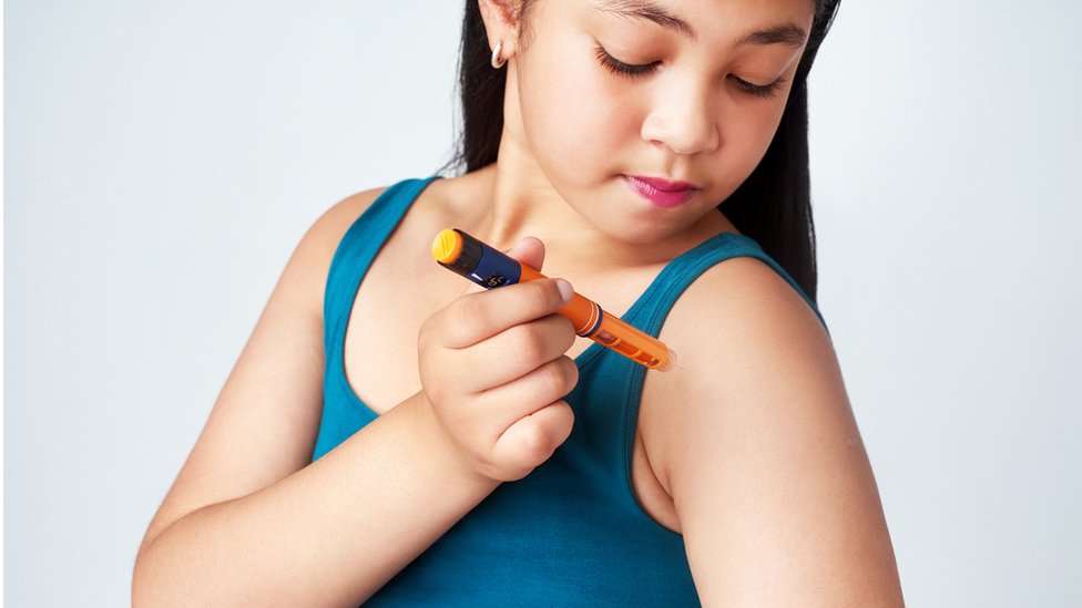 A girl giving herself a shot of insulin