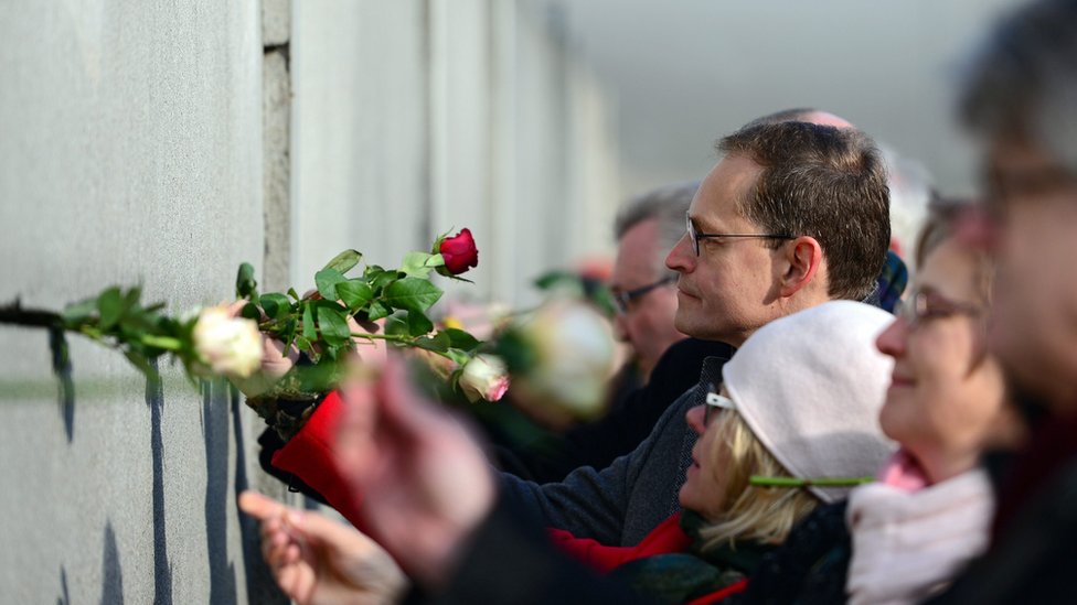Мэр Берлина Майкл Мюллер ставит розу в трещину во время центрального мероприятия, посвященного мирной революции 1989 года в ГДР.