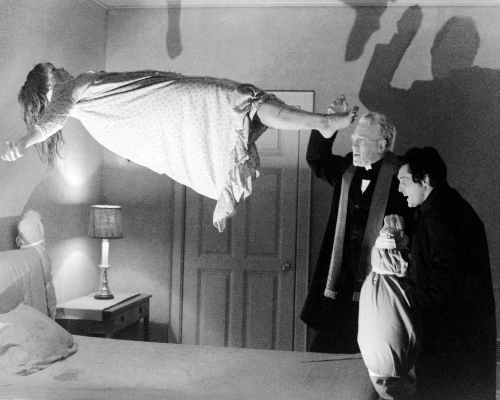 Una escena de "El exorcista", en la que la niña poseída se eleva de la cama frente a dos sacerdotes que conjuran al demonio