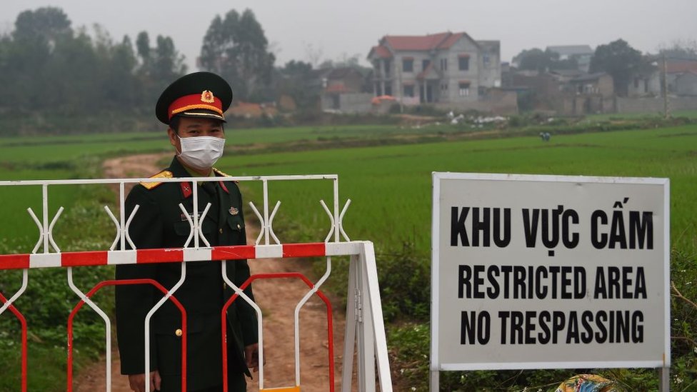Seorang petugas Tentara Rakyat Vietnam mengenakan masker menjaga perbatasan desa Son Loi, 20 Februari 2020.