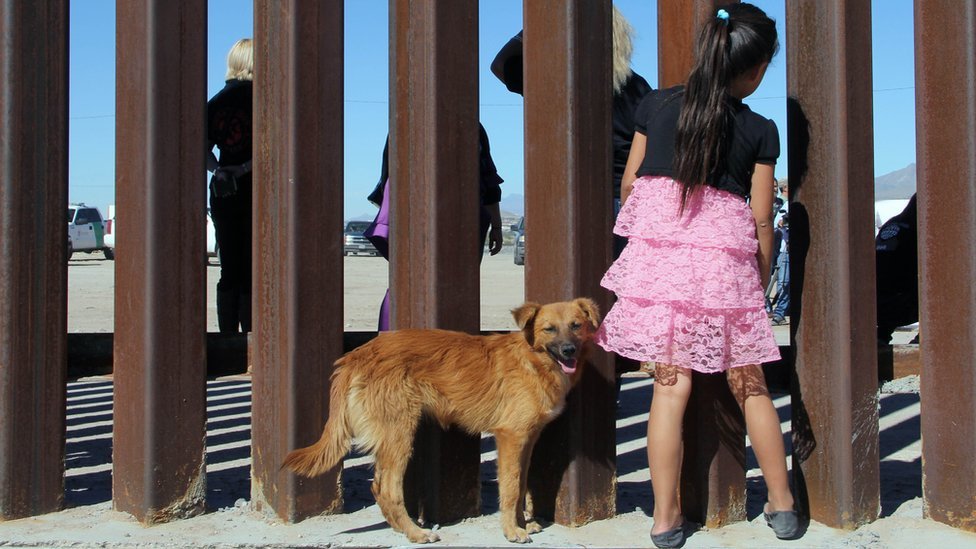 una niña en México mira a través de la frontera.