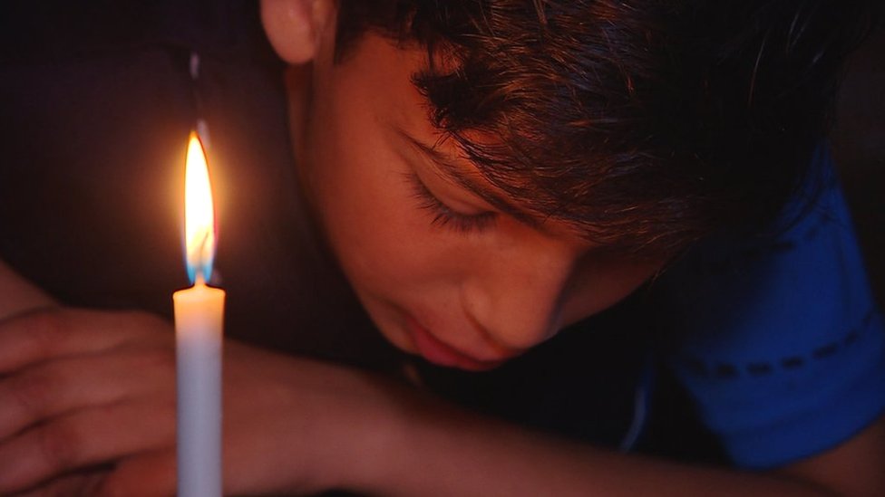 A Palestinian boy poses behind candles during a power outage