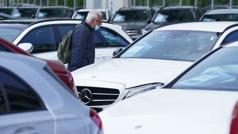 Мужчина смотрит на автомобили, выставленные на продажу в автосалоне в Германии 5 мая 2020 года
