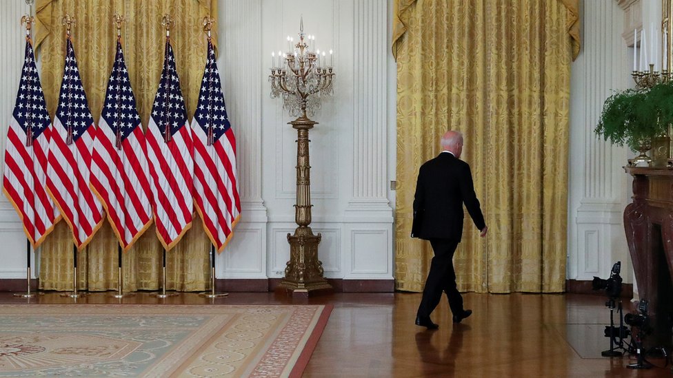 El presidente Joe Biden -de espaldas- se aleja del podio en la Casa Blanca donde habló justificando el retiro de EE.UU. de Afganistán