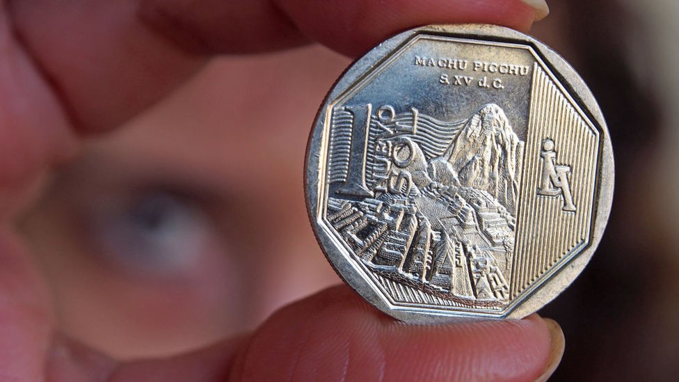 Persona con una moneda peruana en la mano
