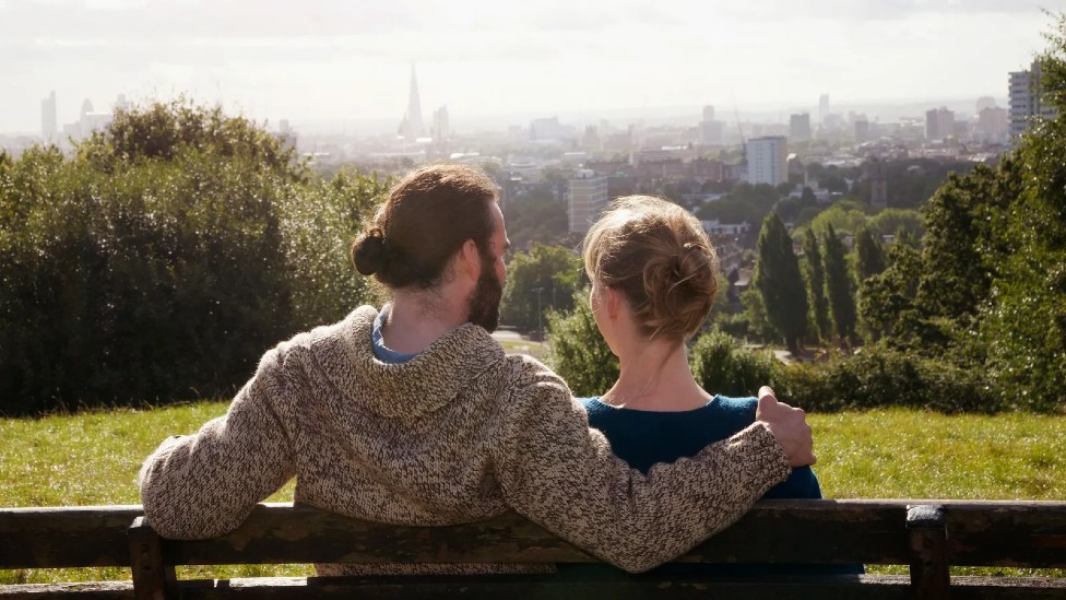 Un hombre y una mujer en pareja sentados en el banco de un parque