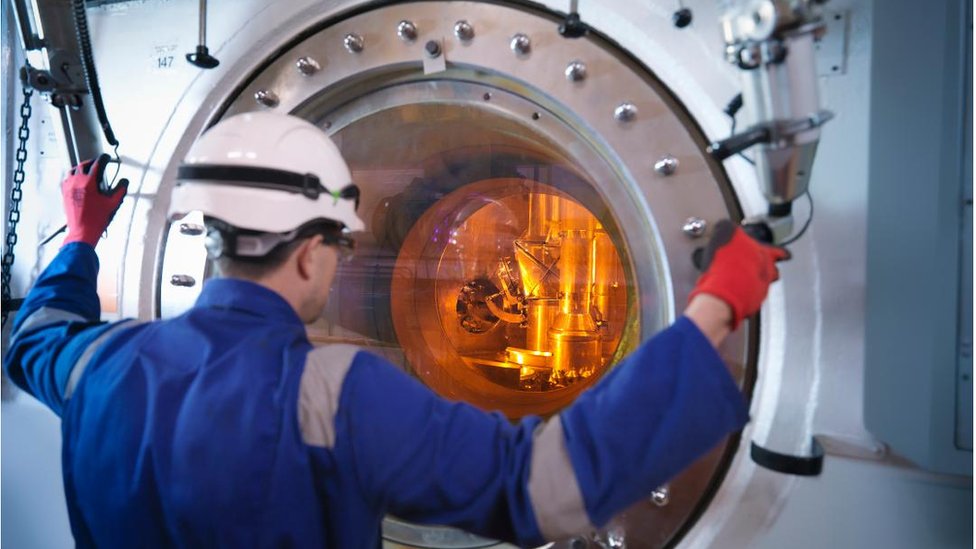 Engineer with fuel rod handling machine in nuclear power station