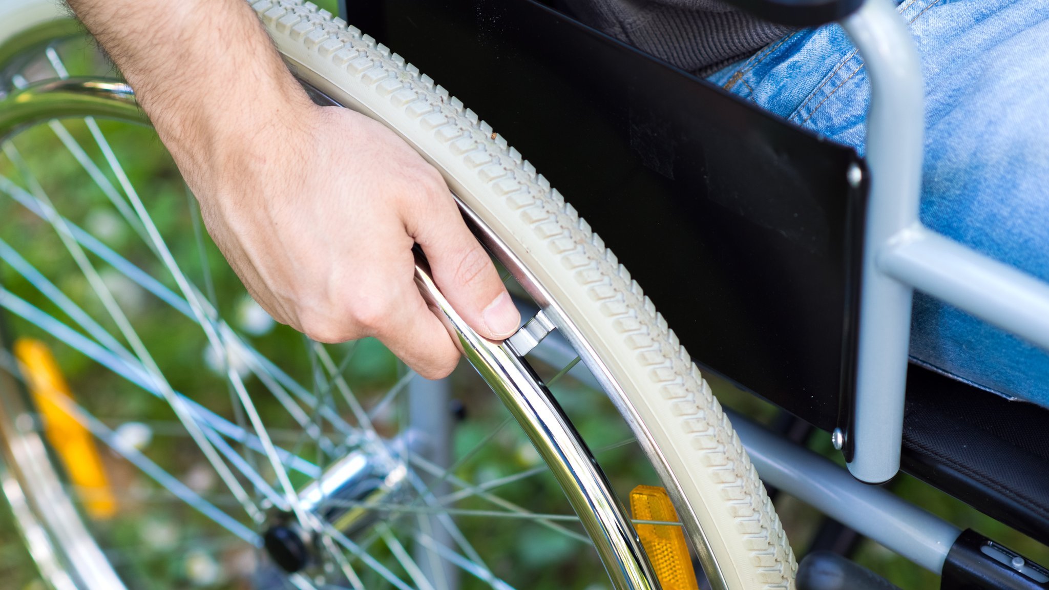 Мужчина держит руку на колесе инвалидной коляски