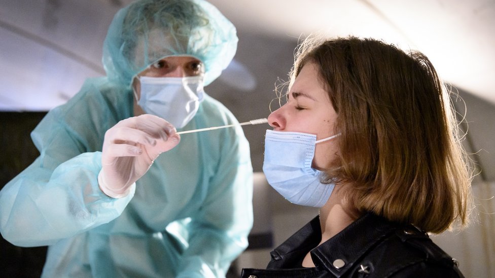 Una enfermera introduce un hisopo en la nariz de una joven durante una prueba de covid