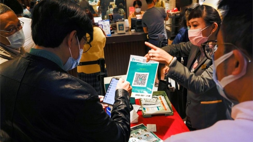 A staff member holds a QR code for the "LeaveHomeSafe" COVID-19 contact-tracing app to consumers at a restaurant, following the coronavirus disease (COVID-19) outbreak, in Hong Kong, China February 18, 2021