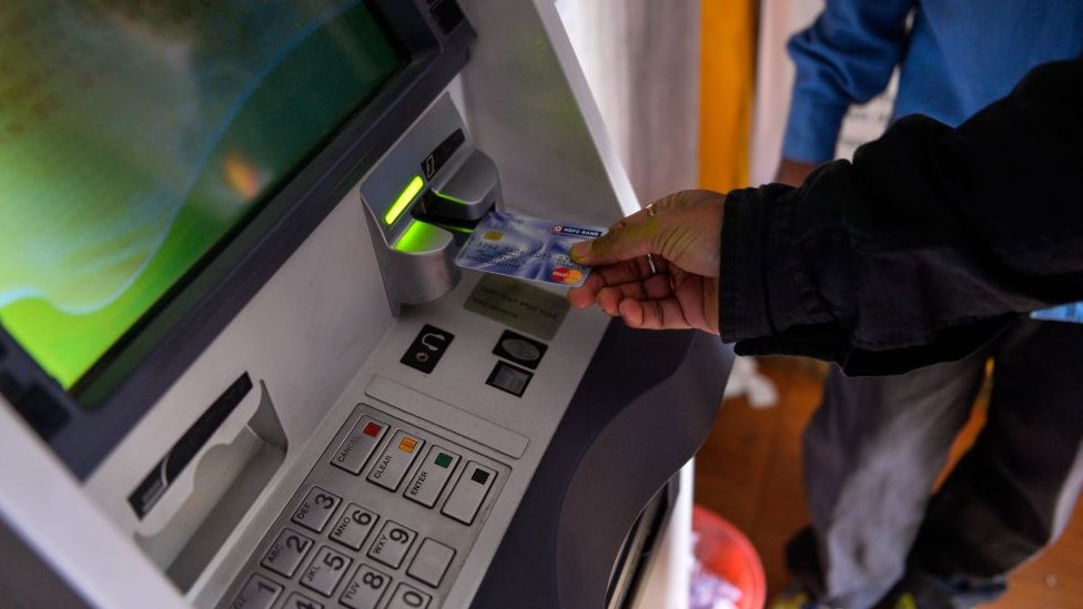 Индийский мужчина вставляет свою карту, чтобы снять деньги в банкомате мобильного банка в Нью-Дели 15 ноября 2016 года.