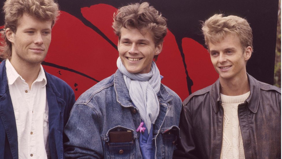 Três jovens brancos e loiros nos anos 1980