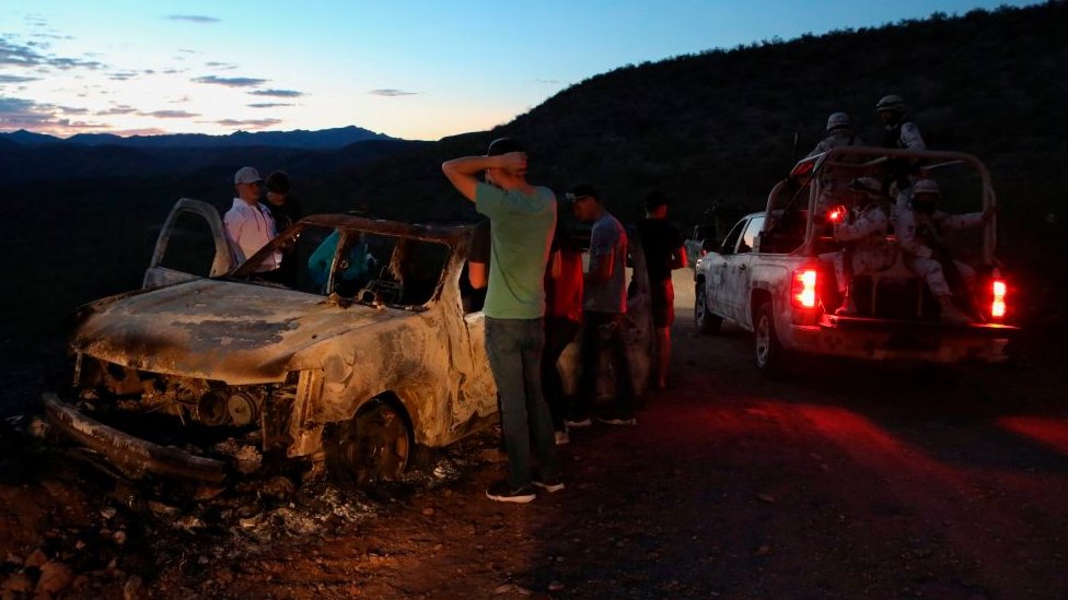Miembros de la familia LeBarón observan el automóvil quemado donde viajaban algunas de las nueve víctimas asesinadas en México