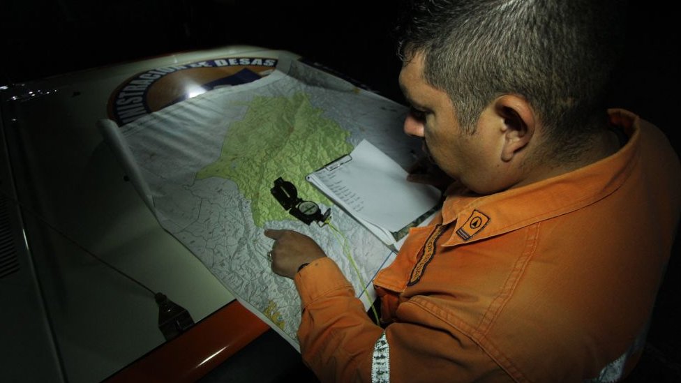 Un miembro de Protección Civil marca un punto en un mapa donde pretenden iniciar un operativo de búsqueda de miembros de un grupo religioso que continúan desaparecidos en el estado Táchira.