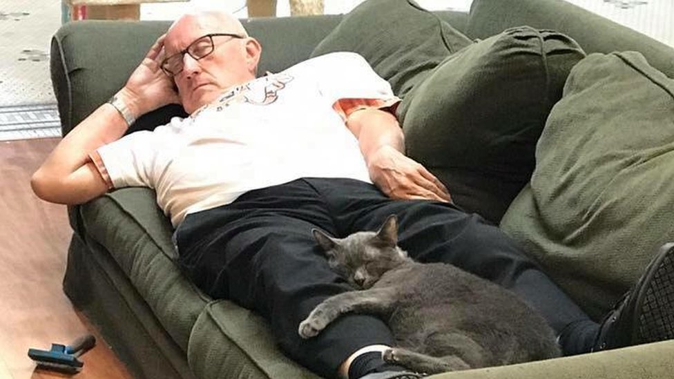 Terry dormido con un gato gris sobre sus piernas