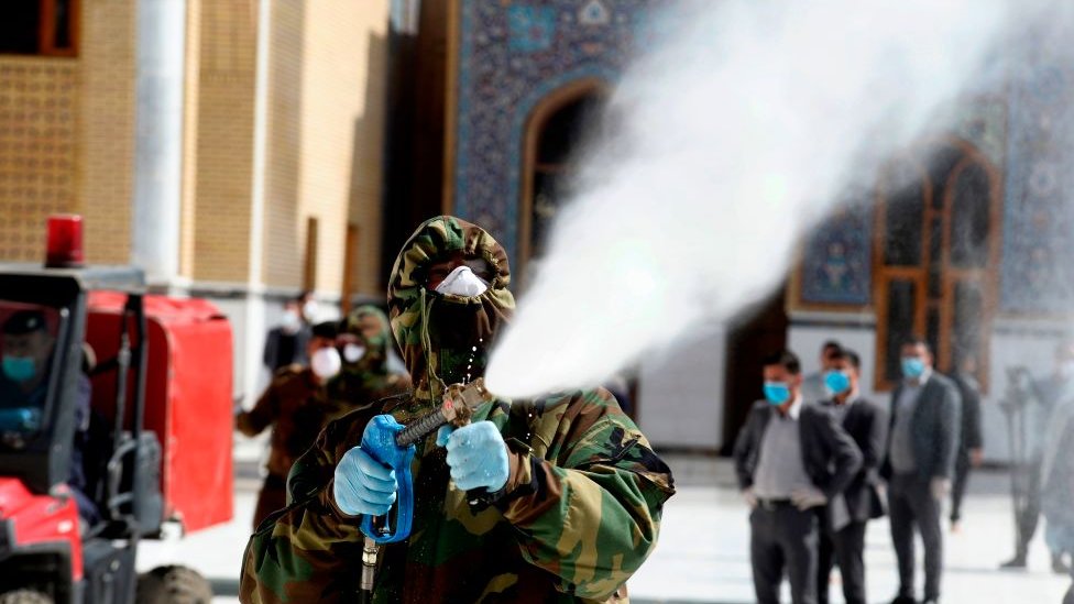 A member of the Iraqi civil defense sprays disinfectant on and around the Great Mosque of Kufa