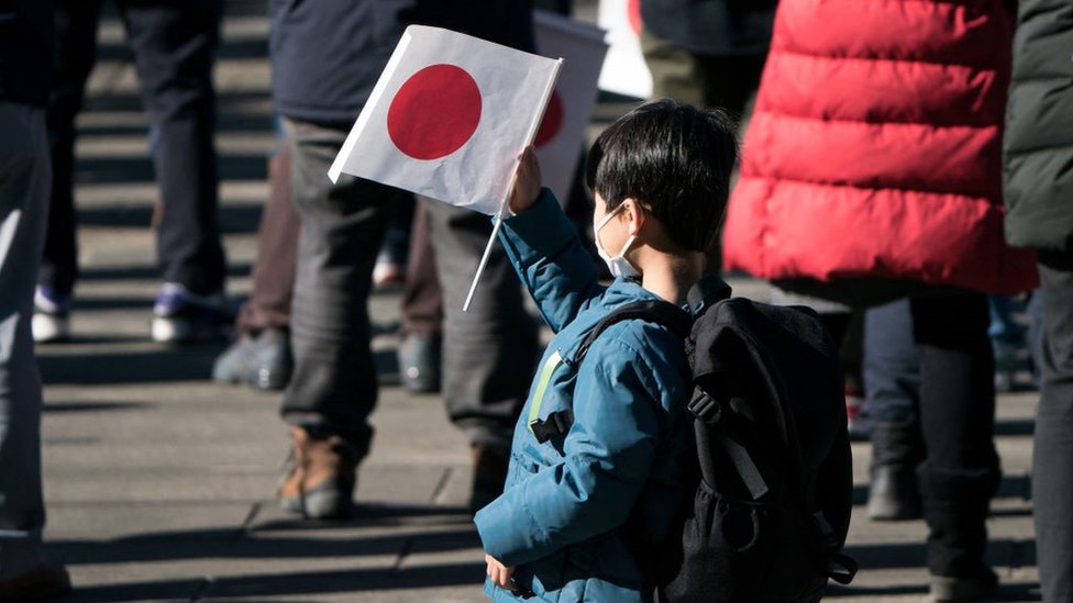 Un niño sostiene una bandera de Japón