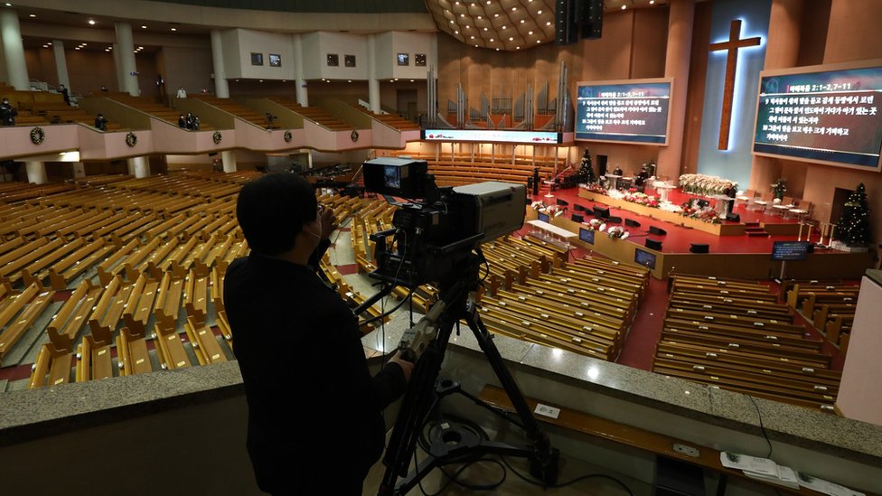 عامل يشغل كاميرا للبث المباشر لخدمة عيد الميلاد التي يتم بثها عبر الإنترنت من كنيسة Yoido Full Gospel حيث يتم اتخاذ تدابير للحماية من انتشار فيروس كورونا (COVID-19) في 25 ديسمبر 2020 في سيول ، كوريا الجنوبية.