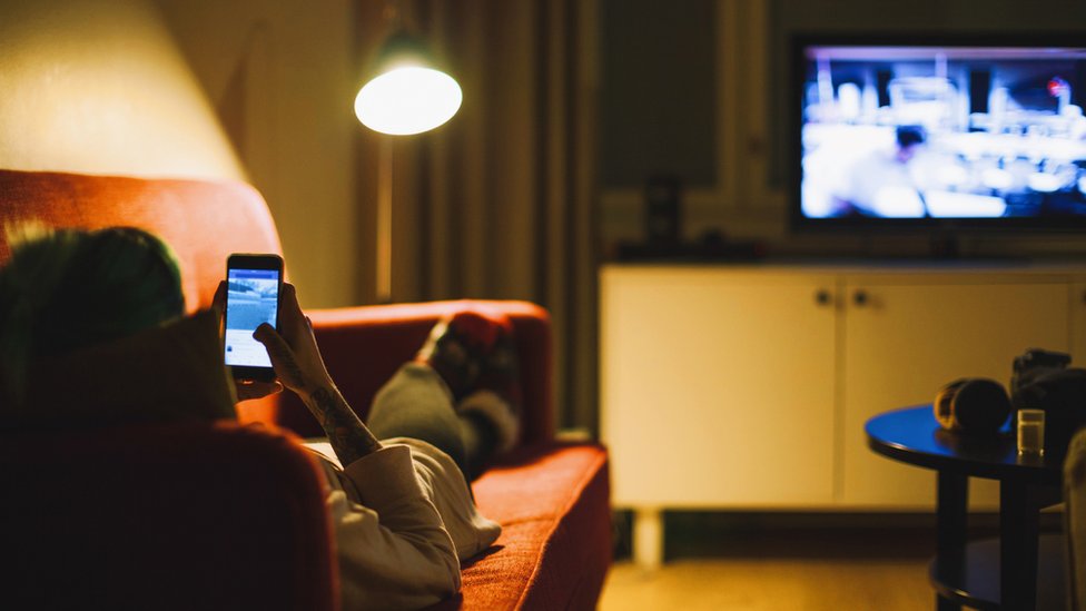 Mujer con celular y televisión.