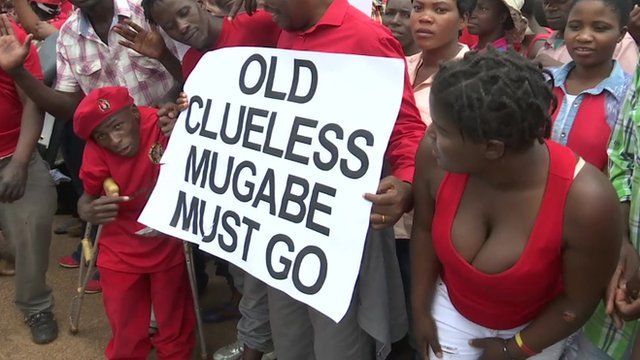 Protesters holding a sign reading 'Old clueless Mugabe must go'