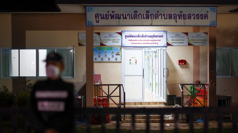 Seorang petugas polisi berjaga di luar tempat penitipan anak tempat terjadinya penembakan massal, di kota Uthai Sawan, 500 kilometer dari Bangkok.