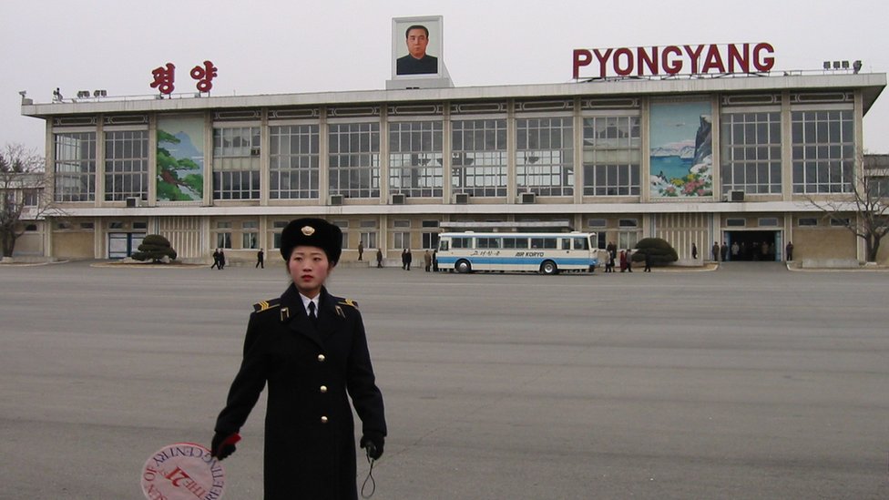 En el Aeropuerto Internacional Sunan de Pyongyang una guardia lleva una señal que dice: "El Sol del Siglo XXI" en honor a Kim Jong Il. Aeropuerto Internacional de Pyongyang