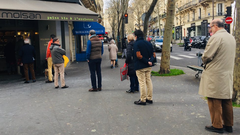 Paris'te baget ekmeği almak için sıraya girenler, aralarına mesafe koymaya dikkat ediyor