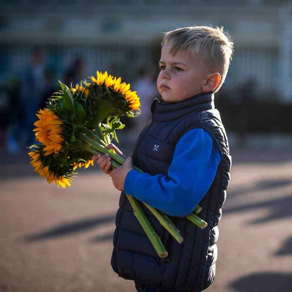 A young boy holding a bunch of sunflowers.