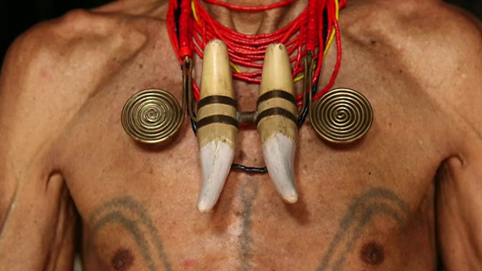 An Indian headhunter showing off his tattoos