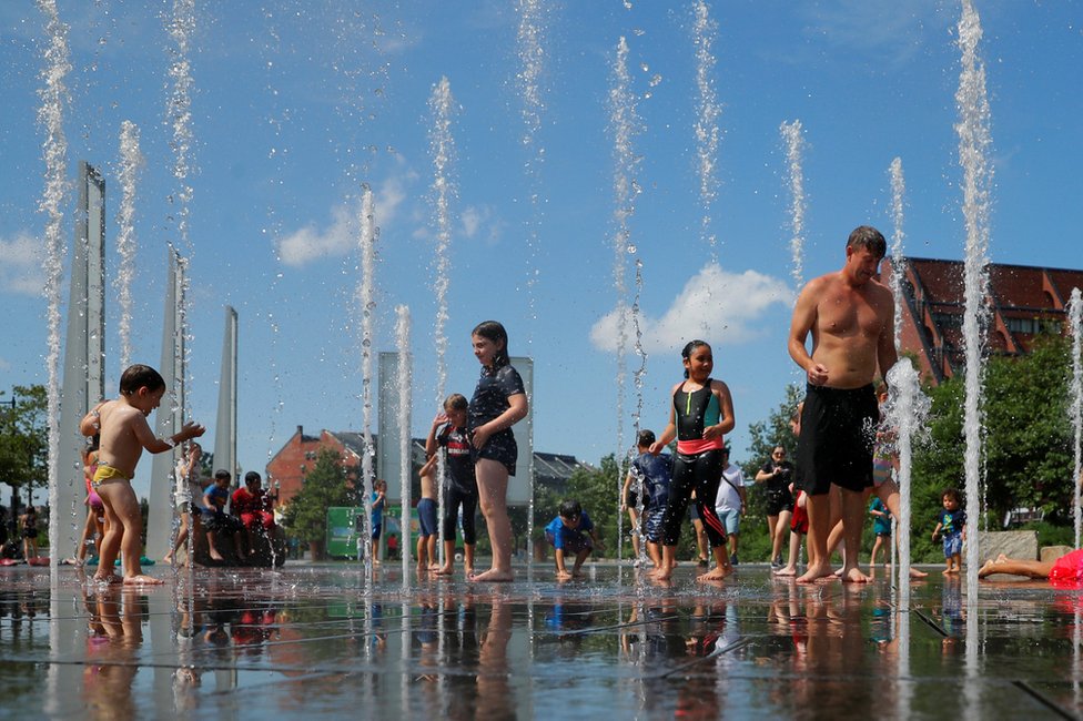 أطفال وكبار يستممتعون بماء النافورة المنعش في أول أيام موجة الحر الصيفية في بوسطن.
