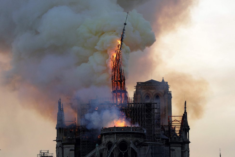 The spire of the landmark Notre-Dame Cathedral collapses as the cathedral is engulfed in flames in Paris on 15 April 2019.
