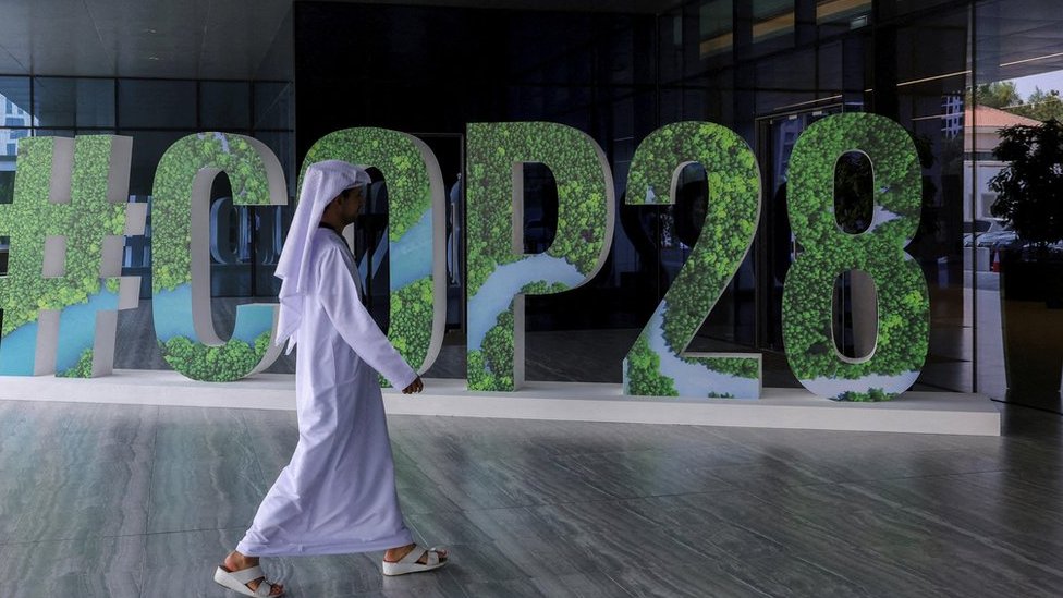 Man walking in front of COP28 sign