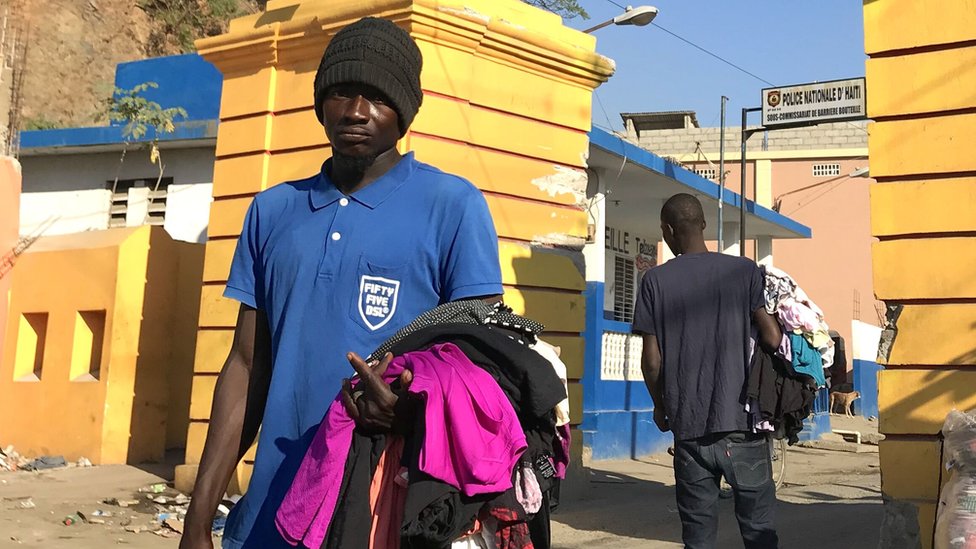 Мужчина продает подержанную одежду на улицах Гаити