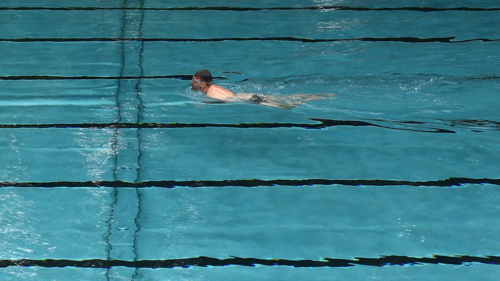Мужчина плавает в пустом бассейне