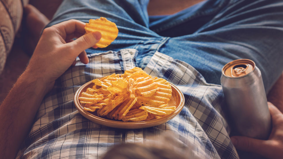 Un hombre comiendo papas fritas y tomando un refresco.