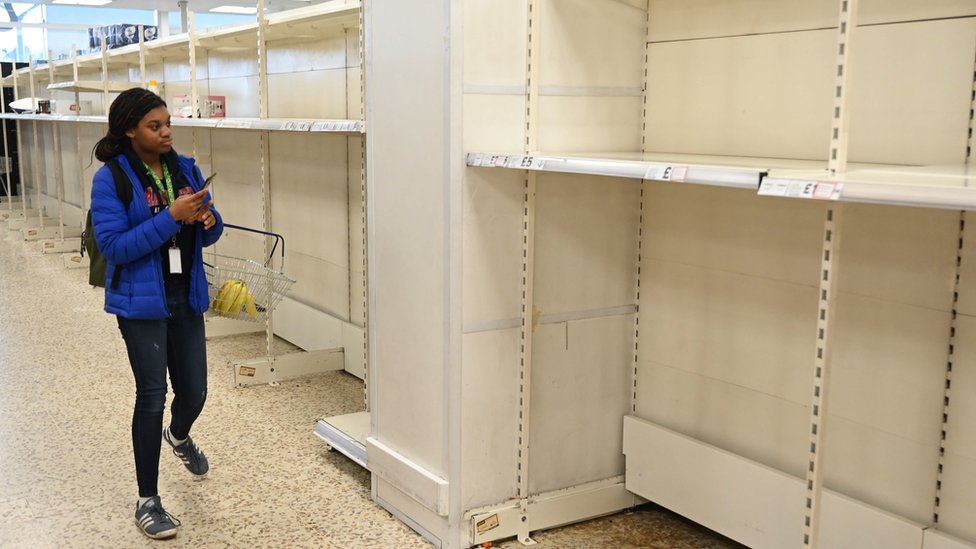 Покупатель смотрит на полки супермаркетов, оставшиеся пустыми после панической покупки рулонов туалетной бумаги