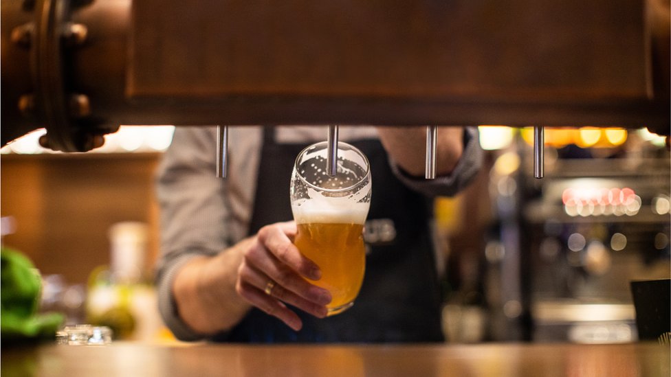 Unrecognizable man pouring a beer on beer tap in drinking glass, in a pub