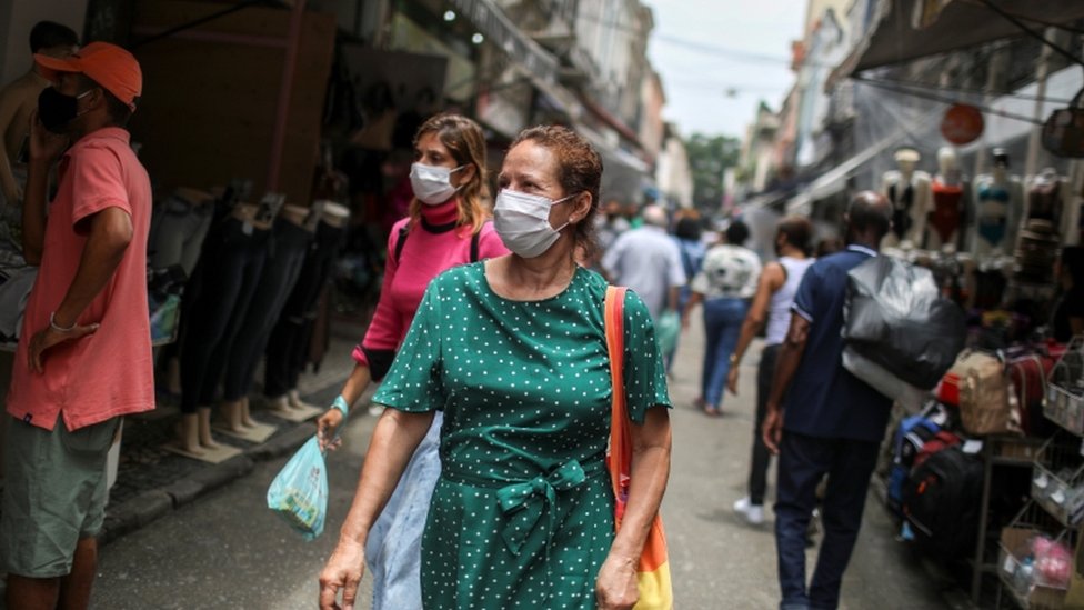 Pessoas caminhando de máscara no Rio