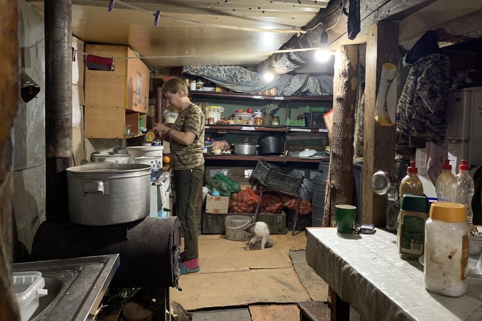 Una soldada ucraniana prepara comida en una cocina improvisada cerca de las líneas del frente