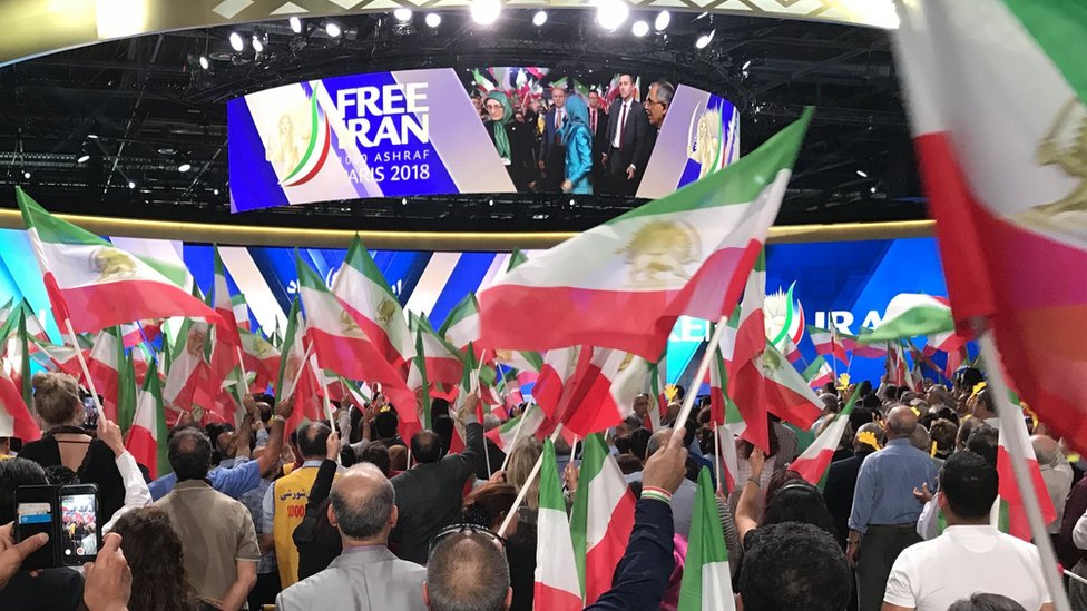 أشخاص يلوحون بالأعلام الإيرانية أثناء التجمع