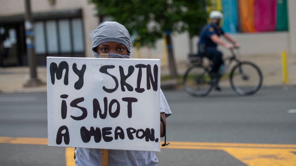 "My skin is not a weapon" says the banner of this protester.