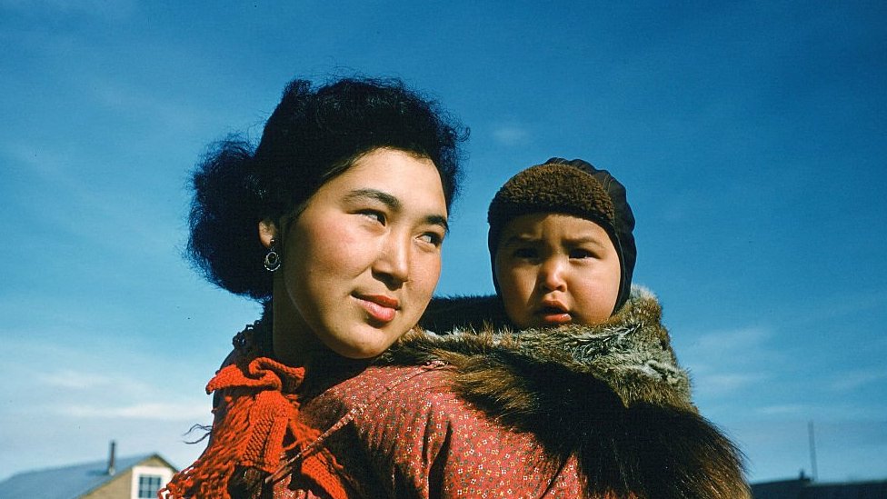 CIRCA 1955: A portrait of an Inuit women and her baby on her back in Unalakleet,Alaska.