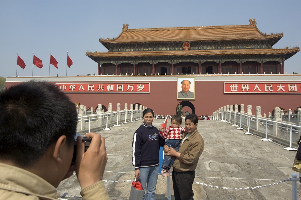 سائحون صينيون يقفون لالتقاط صورة لهم أمام لوحة لماو تسي تونغ أمام بوابة السلام السماوي بساحة تيانينمن
