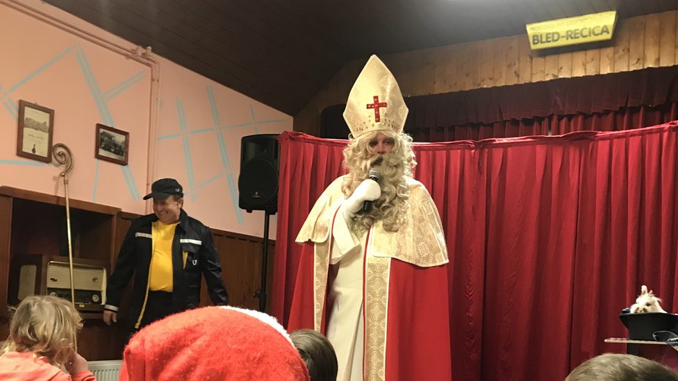 Homem caracterizado de São Nicolau entrega presentes para crianças em festa tradicional em Bled, na Eslovênia