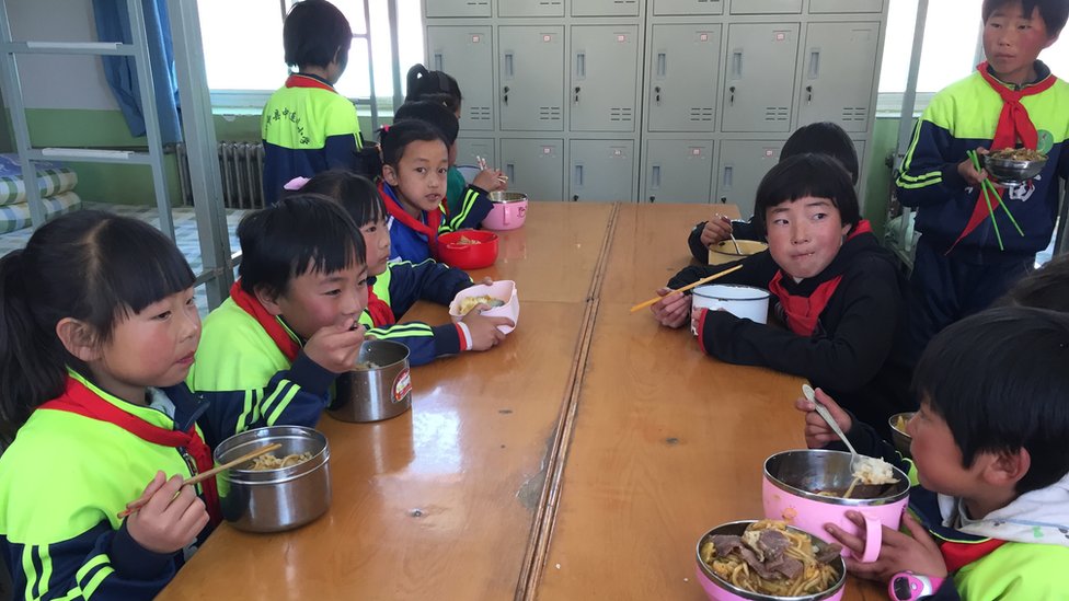 Дети в школе сидят за столом и едят еду