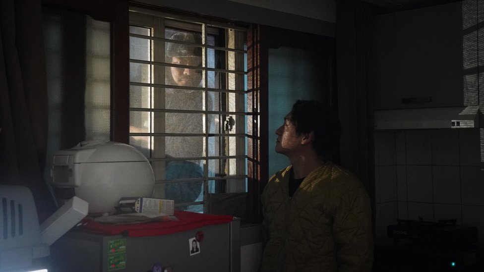 Person looking through the window of Oh kee-cheol's apartment