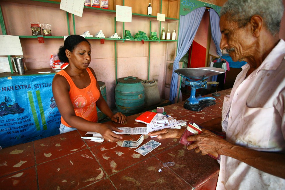 Una mujer en Cuba vende productos a un hombre mayor que le devuelve billetes, en la ciudad de Trinidad.