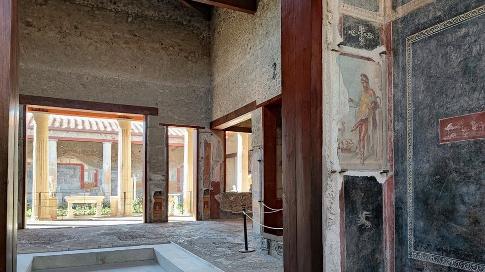 Pintura na parede mostra o deus Príapo pesando seu próprio falo contra um saco de dinheiro
