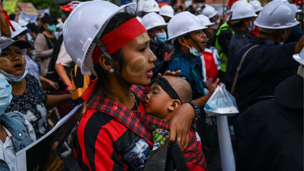 Seorang ibu yang ikut protes menggendong bayinya di Yangon.