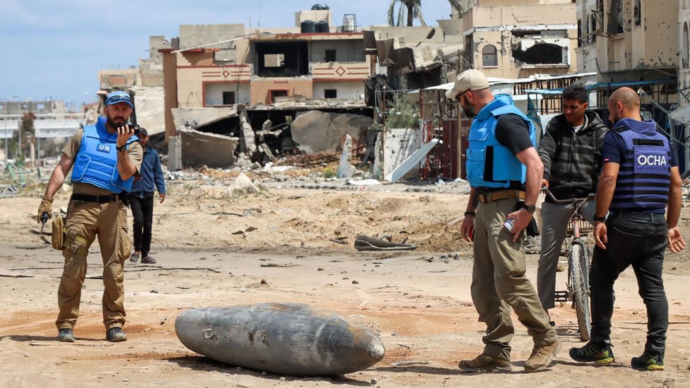 A UN team inspects an unexploded 1,000lb (450kg) bomb lying on a main road in Khan Younis on 10 April, 2024.